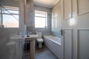 a white bathroom with a sink and a toilet at Elmcroft Apartment - 10 Mins Walk to Woking Town Centre in Woking