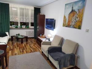 ein Wohnzimmer mit einem Sofa, Stühlen und einem Tisch in der Unterkunft Apartament centrum Kołobrzeg in Kołobrzeg