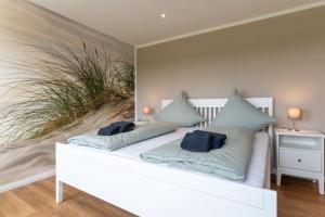 a white bed with blue pillows on top of it at DHH Buhne in Karolinenkoog