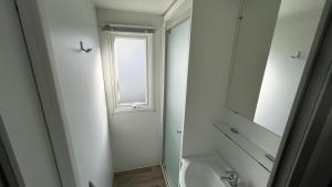 a white bathroom with a sink and a mirror at Mobil homme proche de la mer in Le Grau-du-Roi