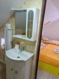 a bathroom with a sink and a mirror and a bed at Pensiunea Constanta in Bran