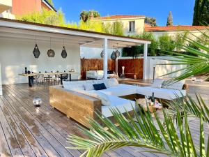 un patio con sofás blancos y una terraza de madera. en Villa Folie, en Roquebrune-Cap-Martin