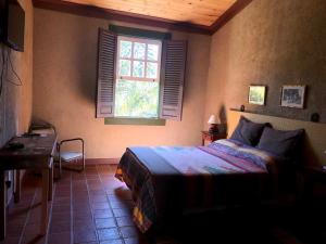 a bedroom with a bed and a window at Pousada Condado Santa Maria in Baependi