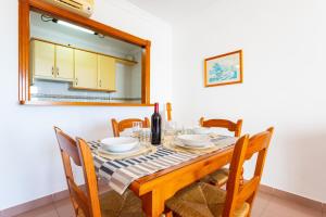 a dining room with a table with chairs and a bottle of wine at Apartamentos Solset Nerja in Nerja