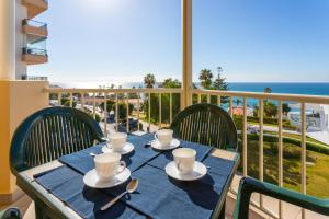 a table with cups and saucers on a balcony with the ocean at Apartamentos Solset Nerja in Nerja