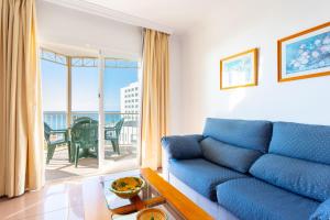 a living room with a blue couch and a balcony at Apartamentos Solset Nerja in Nerja