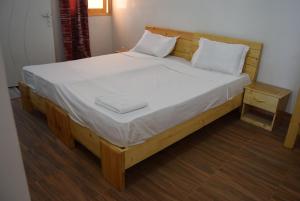 a large wooden bed with white sheets and pillows at Hotel Berges du Sine in Fatick
