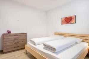 una cama con sábanas blancas y una foto del corazón en la pared en Talhaus - Rita, en Ponte Nova