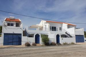 a white house with blue garage doors on a street at Villa Sol e Mar - Vila do Maio - Ponta Preta in Vila do Porto