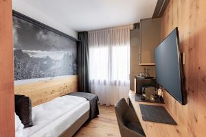 a hotel room with a bed and a flat screen tv at Landhaus Boutique Motel - contactless check-in in Nendeln