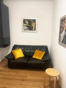 um sofá de couro preto numa sala de estar com almofadas amarelas em Piccolo appartamento nel cuore di Trieste em Trieste