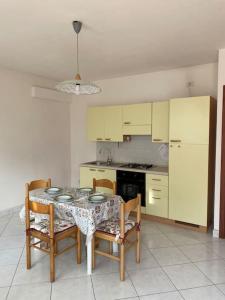 une cuisine avec une table et des chaises et une cuisine avec des armoires jaunes dans l'établissement La casa al mare di Mary - Bilocale, à Roseto degli Abruzzi