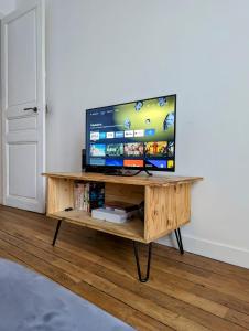 TV en una mesa de madera en una habitación en Charming 51m In Aubervilliers, en Aubervilliers