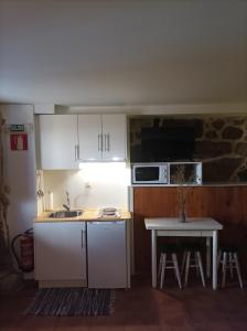 uma cozinha com armários brancos e uma mesa com um micro-ondas em Habitación do Xurés em Maus de Salas