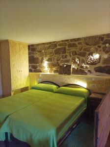 um quarto com uma cama verde e uma parede de pedra em Habitación do Xurés em Maus de Salas