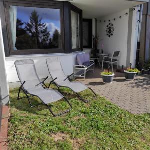 two chairs sitting in the grass on a patio at FeWo Harzer Weitblick Hunde Willkommen, W Lan, 2x Smart TV in Braunlage
