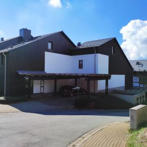 a large black house with a car parked in front of it at FeWo Harzer Weitblick Hunde Willkommen, W Lan, 2x Smart TV in Braunlage
