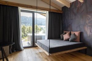 una camera da letto con un letto e una grande finestra di Alpuris - Your Boutique Suite - Hotel B&B a Cavalese