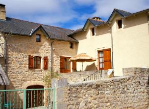 a house with a stone wall and a fence at Aux coeurs du Méjean in Mas Saint-Chély