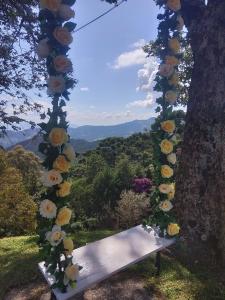 un banco sentado bajo un árbol con flores. en Pousada Village Pôr do Sol en Campos do Jordão