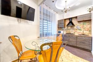 1-room VIP apartment in the Druzhby Narodiv metro station في كييف: غرفة طعام مع طاولة زجاجية وكراسي صفراء