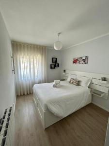 a white bedroom with a large bed and a window at Divine Waves - Cabedelo in Viana do Castelo