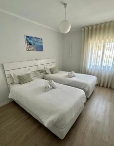 two beds in a hotel room with white sheets at Divine Waves - Cabedelo in Viana do Castelo