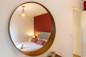 a circular mirror in a bedroom with a bed at Happy Loft - Centre historique + parking privé in Blois
