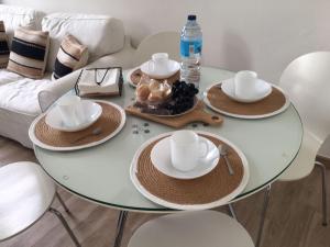 una mesa de cristal con sombreros y platos y una botella de agua en Casa dos Cantares, en Padrón