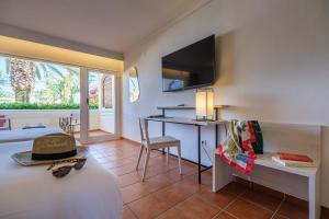 a room with a bed and a table and a desk at Oassium Hotel - Adults Only in La Pineda