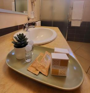 un bancone del bagno con lavandino e un vassoio con scatole di Hotel Federico II a Castiglione di Sicilia