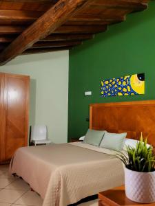 a bedroom with a bed with a green wall at Hotel Federico II in Castiglione di Sicilia