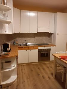 a kitchen with white cabinets and a wooden floor at Sunshine GuestHouse in Cannero Riviera