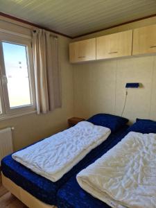 two beds in a small room with a window at kreeft 171 in Ballum