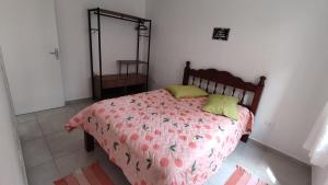 a bedroom with a bed with a pink comforter at Ap23 Cristal do Indaiá I 450m praia in Bertioga