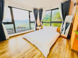 a bedroom with a bed and large windows at Pine Forest House Dalat in Xuan An