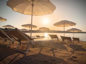 a group of chairs and umbrellas on a beach at Hotel Pedra Santa in Baja Sardinia