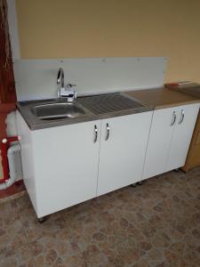 a white kitchen with a sink and a counter at Apartman" Ruža" in Višegrad