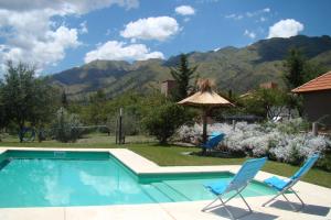 a pool with two chairs and an umbrella and mountains at Rumbo 020 Apart in Merlo