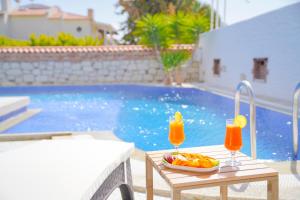 a table with two glasses of orange juice next to a pool at The Fountain Hotel in Çeşme