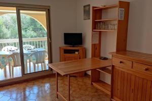 een kamer met een tafel, een televisie en een balkon bij Bel appartement avec piscine proche des plages in Six-Fours-les-Plages
