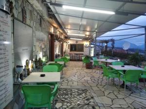 un restaurante con sillas verdes y mesas en un patio en Guest House Bake, en Gjirokastra