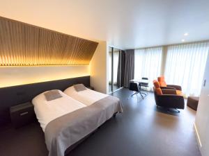 una camera d'albergo con un grande letto e una scrivania di Villa Vindina a De Panne
