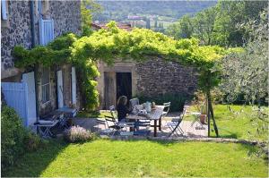 a woman sitting at a table in a garden at Maison spacieuse avec piscine à Saint-Lager-Bressac in Saint-Lager-Bressac
