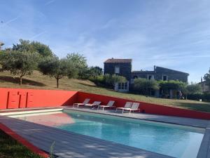 ein Pool mit Stühlen und ein Haus im Hintergrund in der Unterkunft Maison de 5 chambres avec piscine privee jardin clos et wifi a Saint Lager Bressac in Saint-Lager-Bressac