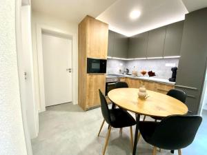a kitchen with a wooden table and black chairs at Apartmán Samuel Prievidza in Prievidza