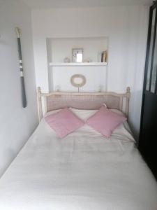 Una cama blanca con dos almohadas rosas. en Tamarina, en Guéthary