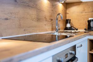 una cucina con lavandino in acciaio inossidabile e parete in legno di Maurerhof Morgenrot a Maranza