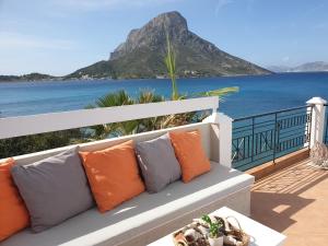 Un sofá blanco con almohadas en un balcón con vistas al océano. en Aegean Villa-On beach apartment! Ideal choice! en Masouri