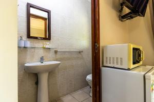 a bathroom with a sink and a microwave on top of a refrigerator at Nyathi Lodge in Richards Bay